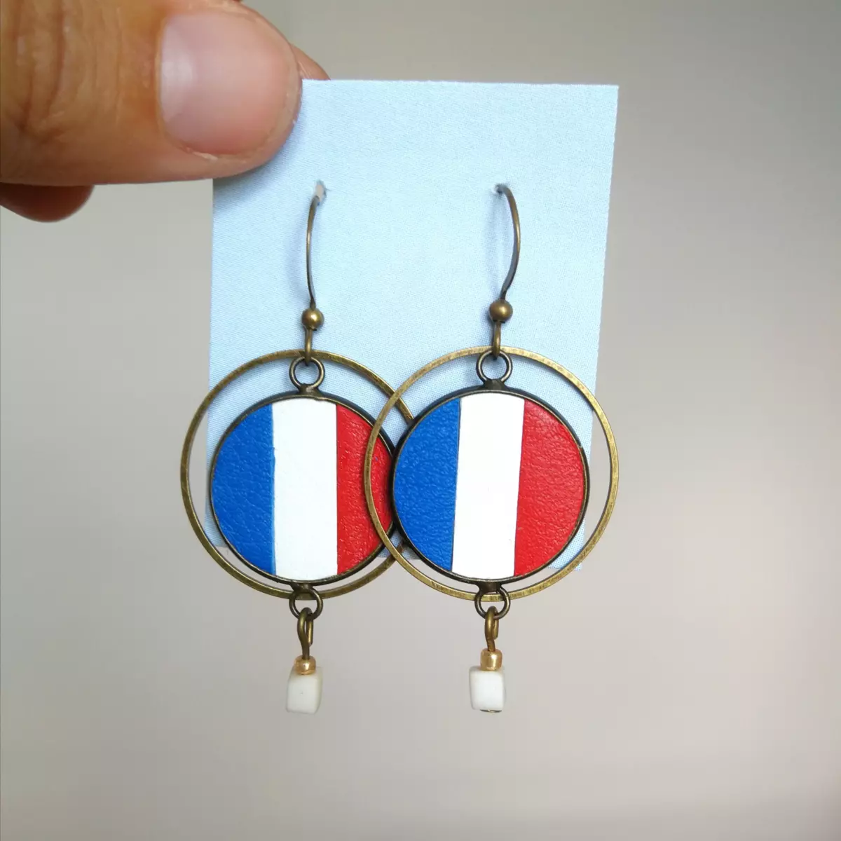 Boucles d'oreilles "drapeaux" en cuir surcyclé bleu blanc rouge créées sur mesure par L'Artelier de Cloth pour Gaëlle Edon, athlète en paratir. Portées lors des cérémonies paralympiques de Paris 2024